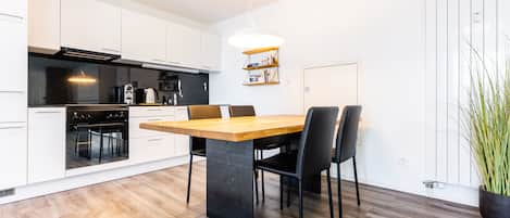Una cocina moderna con armarios blancos, una mesa de comedor de madera y sillas negras.