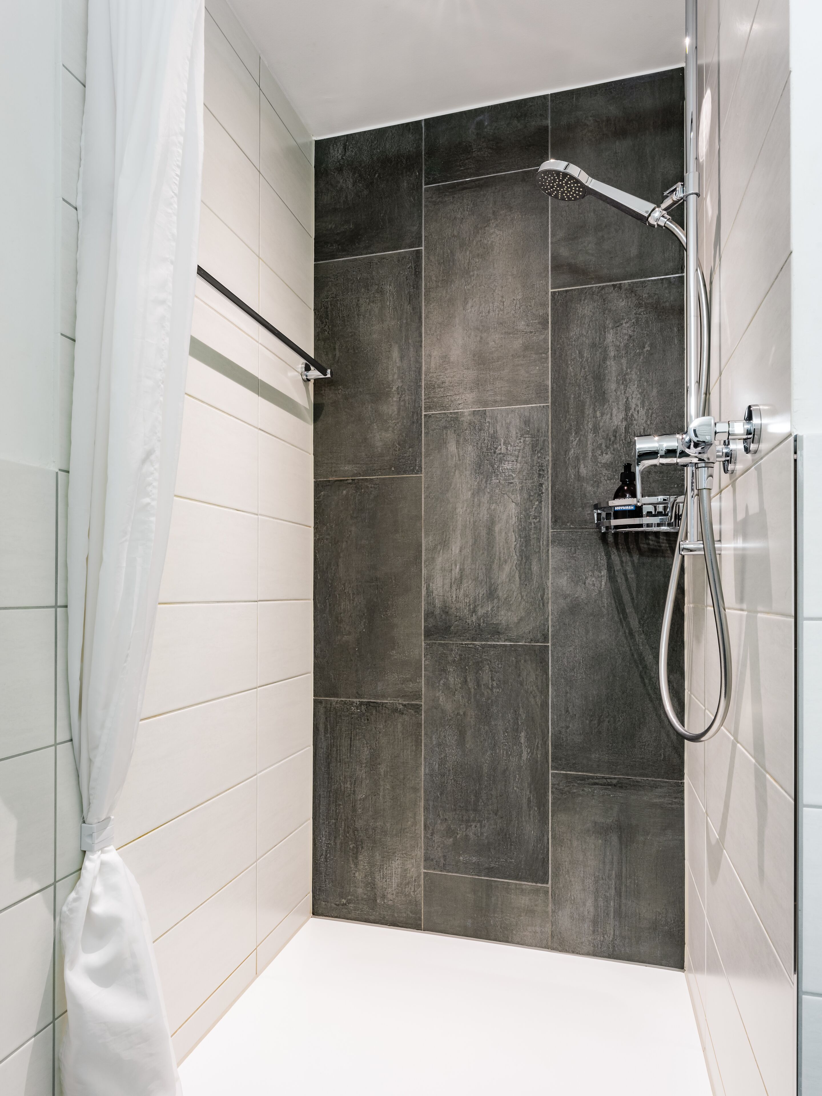 Eine moderne Dusche mit Handbrause und Wandarmatur.