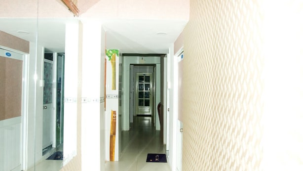 A hotel corridor with a mirrored wall, a door with a green sign, and a tiled floor. - Trinh Ngoc Hotel (Ho Chi Minh City)