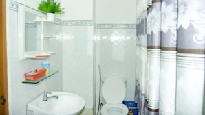 A bathroom with a white sink, a mirror, a toilet, and a shower curtain. - Trinh Ngoc Hotel (Ho Chi Minh City)