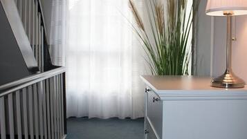 A hallway with a staircase, a white dresser with drawers, a lamp, and a large plant.