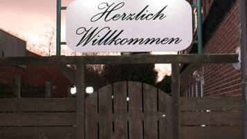 A wooden gate with a sign above it that reads 'Herzlich Willkommen' (Warmly Welcome).