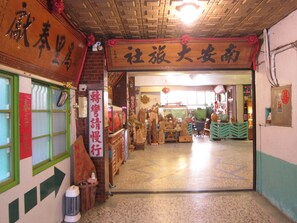 An interior corridor with traditional decorations and signage, leading to a shop area with various items displayed. - Nan An Hotel (Tainan)