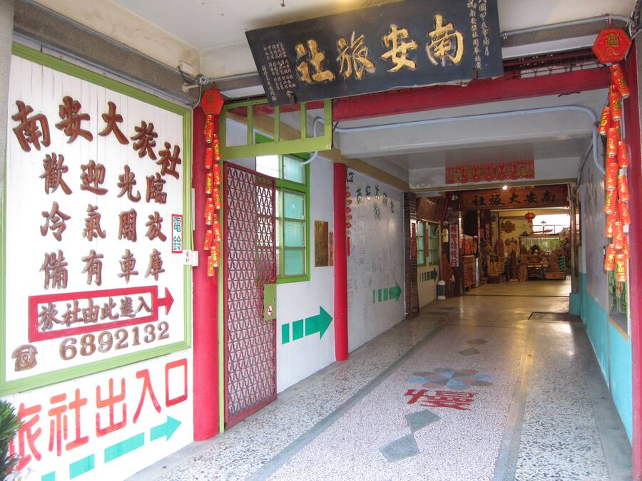 A corridor with directional signs, a door with a red frame, and a shop entrance with Chinese characters.