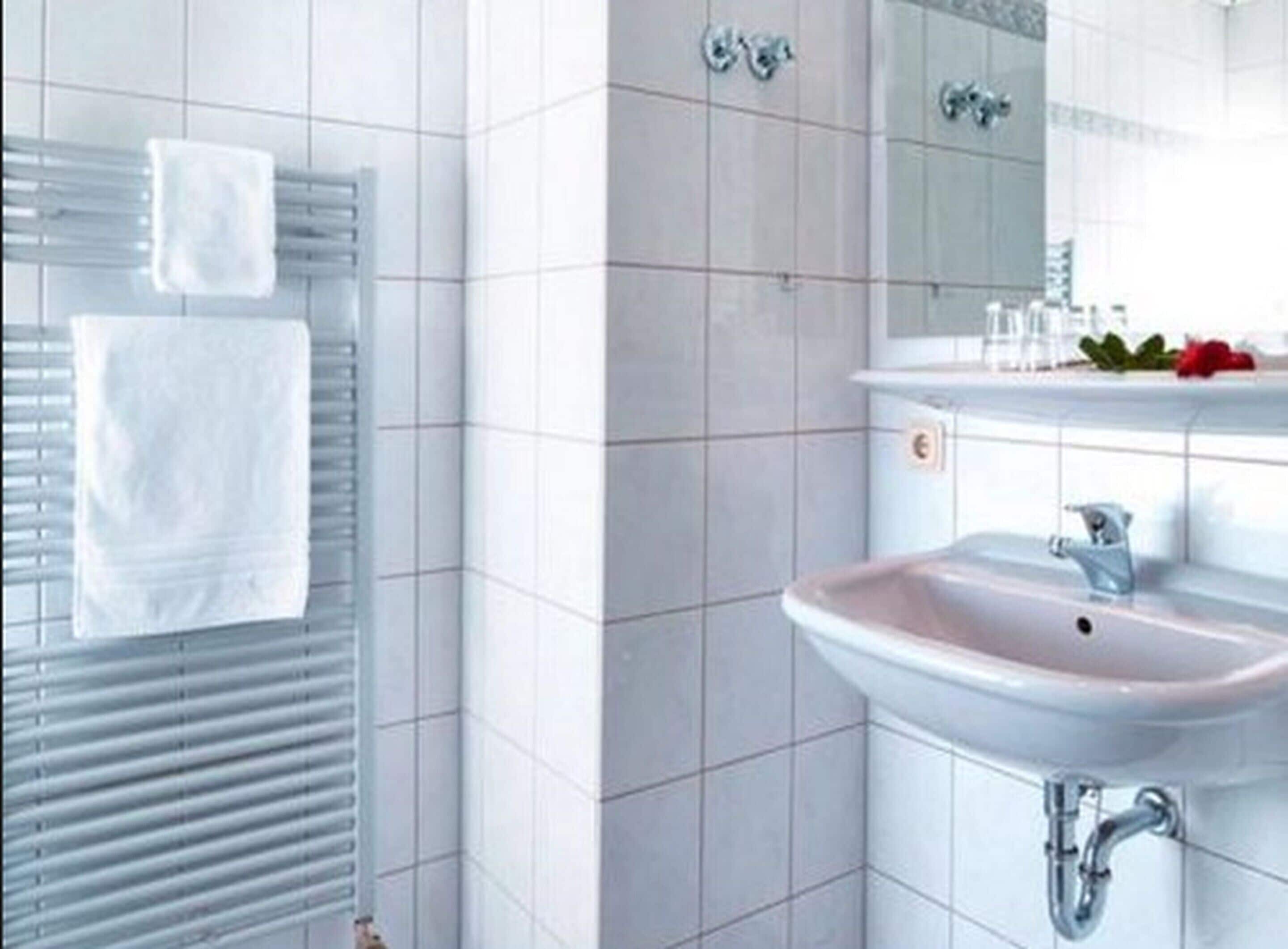 Ein Badezimmer mit einem weißen Waschbecken, einem Spiegel und einem Handtuchhalter.