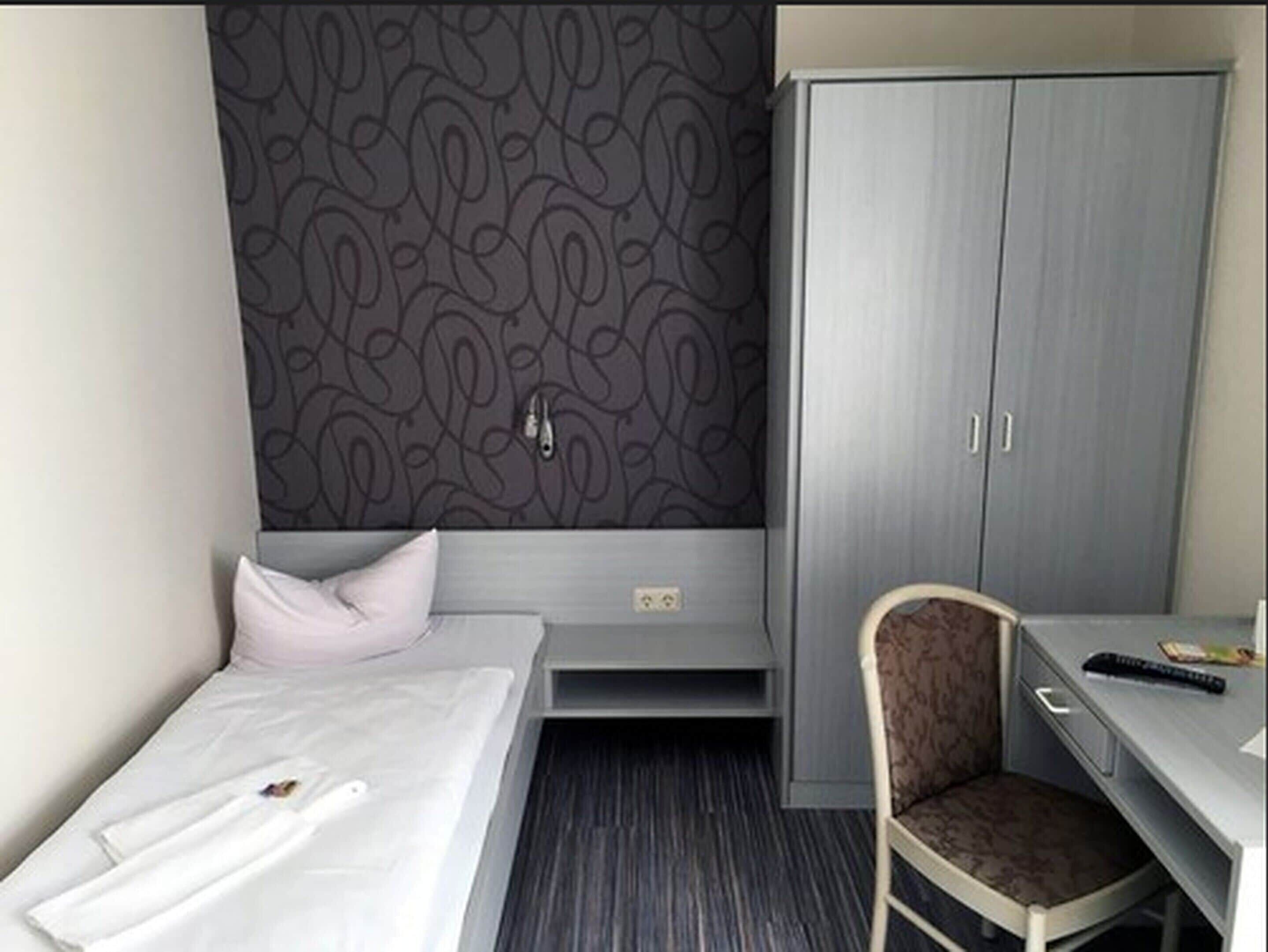 Een hotelkamer met een bed, een bureau, een stoel en een kledingkast.