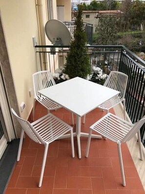 A balcony with a white table and four white chairs, a small Christmas tree, and a satellite dish. - Al Parco Primavera (Sorrento)