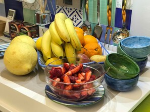 A kitchen counter with a bowl of strawberries, a bunch of bananas, and a melon. - Al Parco Primavera (Sorrento)