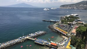 A coastal area with a pier, boats, and a mountainous backdrop. - Al Parco Primavera (Sorrento)