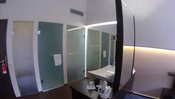 Casa de banho de hotel com um espelho grande, uma pia e um porta-toalhas.