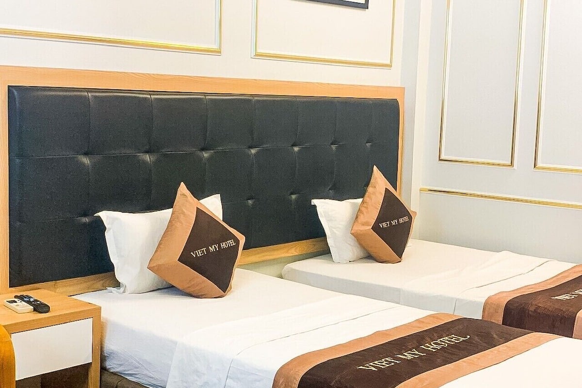 A hotel room with two beds, each with a headboard and pillows labeled "VIET MY HOTEL".