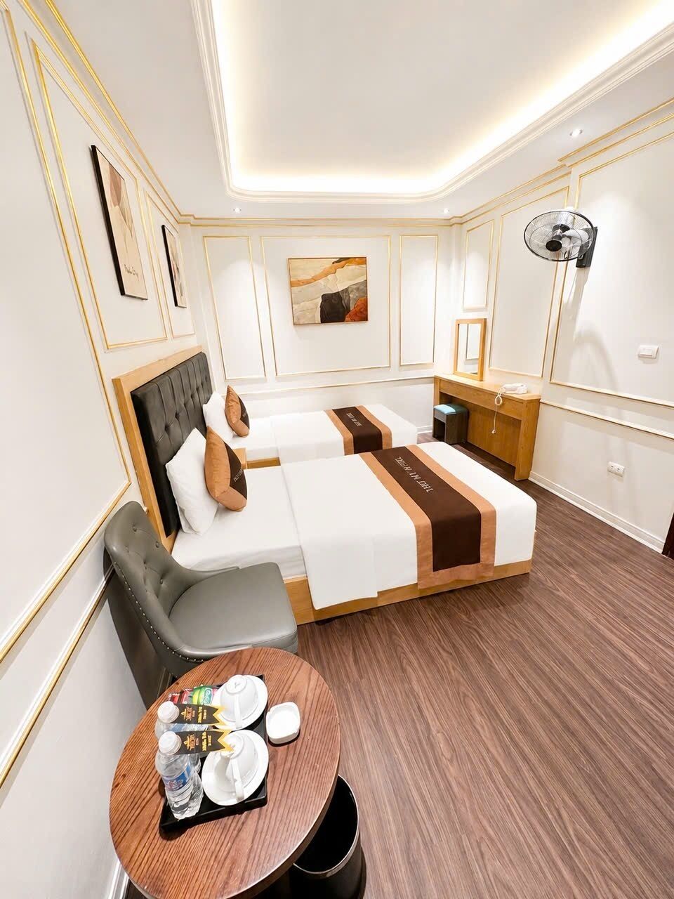 A hotel room with two beds, a seating area, and a small table with amenities.