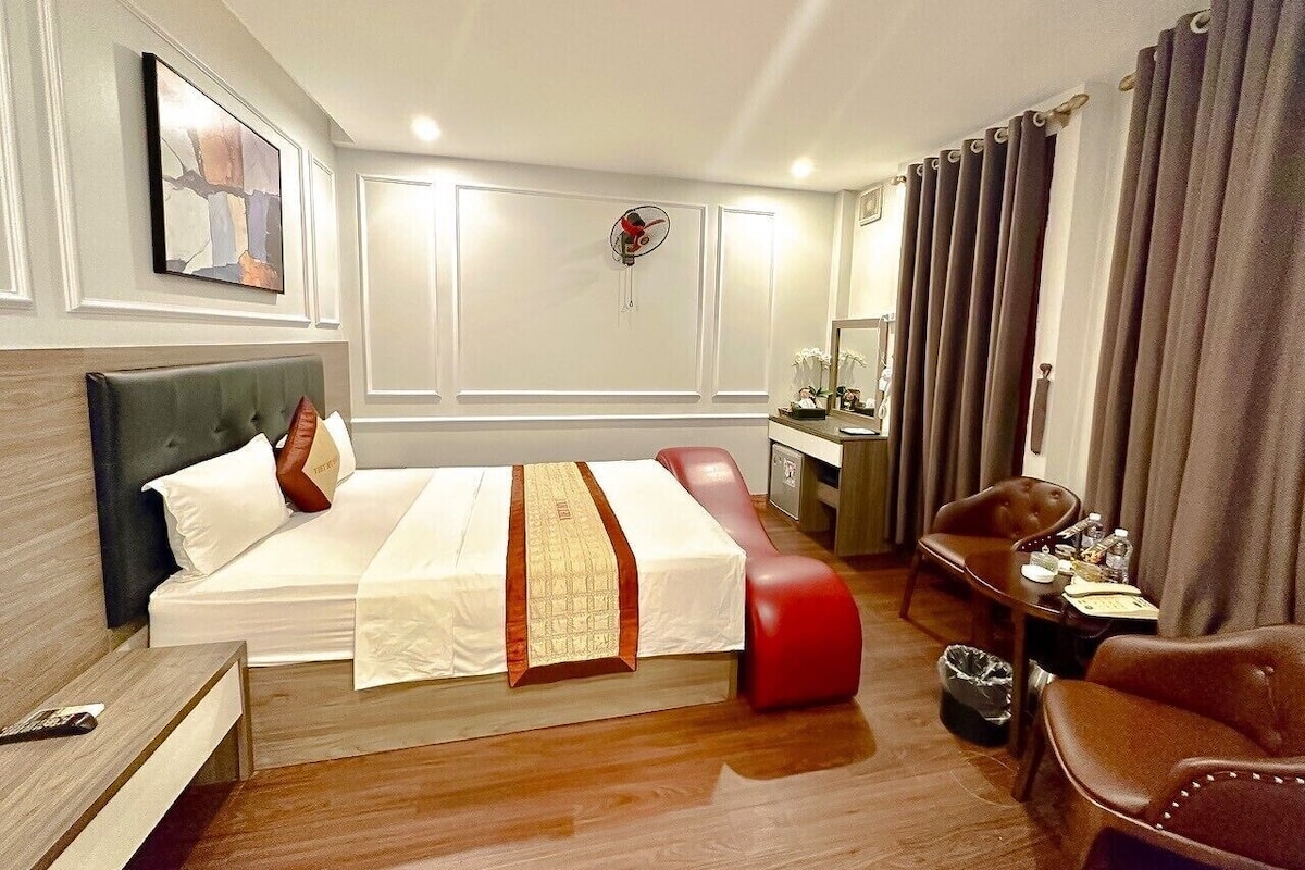 A hotel room with a bed, a desk, a chair, and a small table.