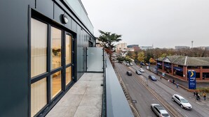 Een modern gebouw met grote ramen en uitzicht op een drukke straat met auto’s en voetgangers.