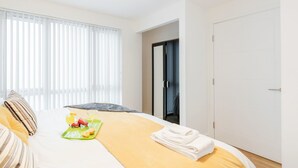 Een hotelkamer met een bed, een dienblad met ontbijtartikelen, een deur en een raam met zonwering.