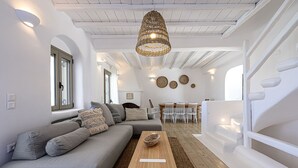 A modern living room with a grey sofa, a wooden coffee table, and a wicker pendant light. - 9 Muses Villas Mykonos (Mykonos)