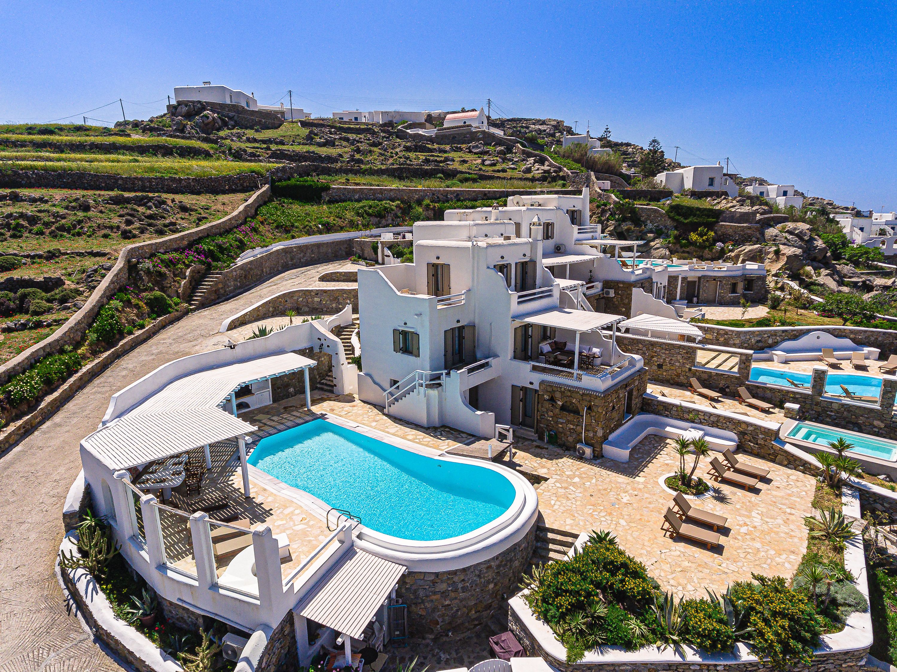 Un complexe hôtelier doté d’une grande piscine centrale, de plusieurs piscines plus petites et offrant une vue sur les collines.