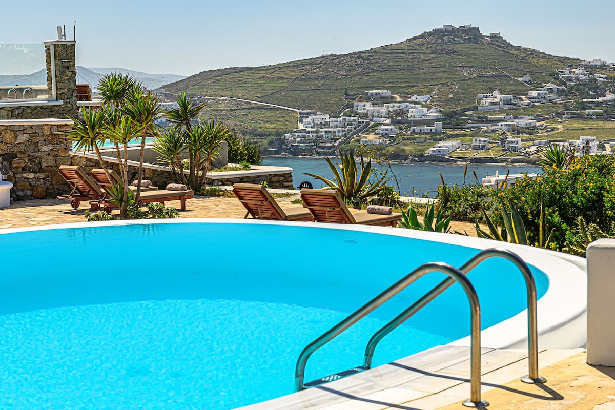 A swimming pool with lounge chairs and a view of a coastal village.