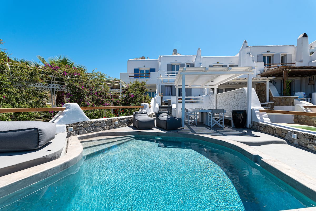 A pool area with lounge chairs and a stone wall.