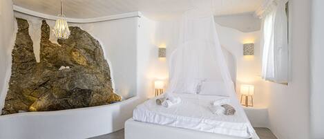 A bedroom with a bed, a large rock wall, and two bedside lamps.