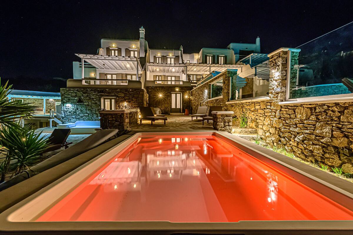 A modern hotel with a swimming pool, stone walls, and outdoor seating.