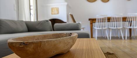 A wooden bowl on a table in a living room with a gray sofa and white chairs.
