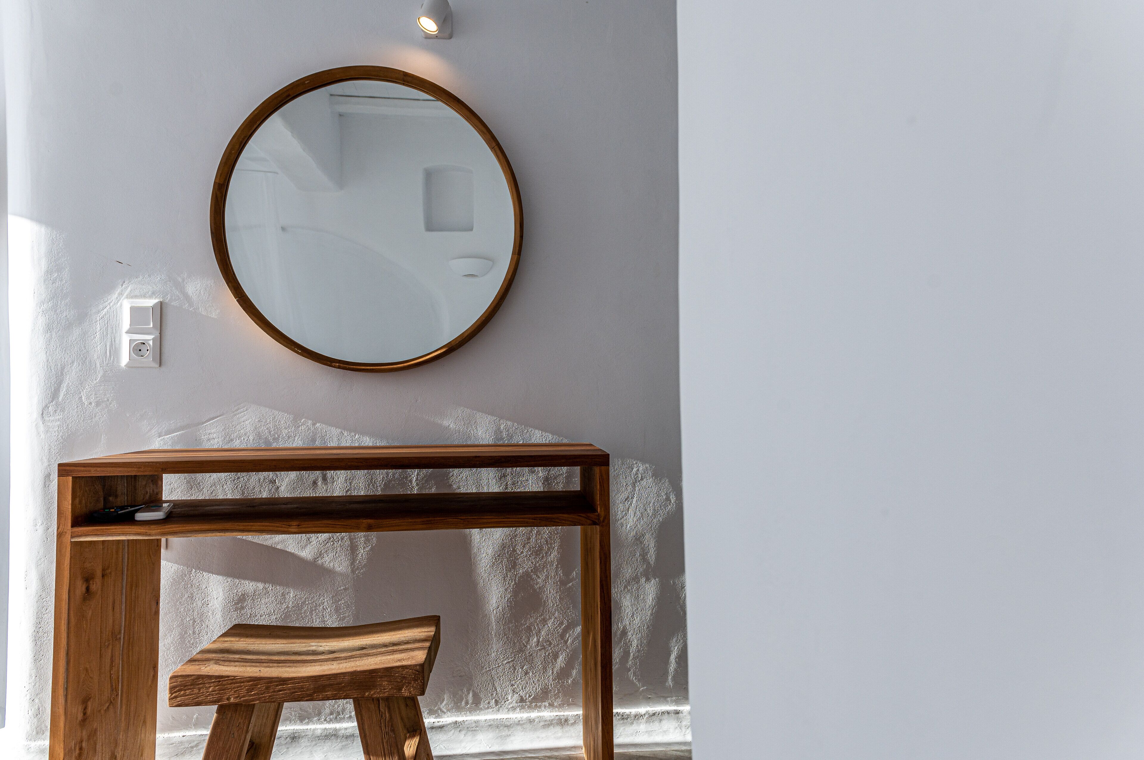 A wooden console table with a mirror above it, set against a textured wall.