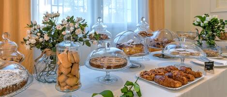 A buffet table with various food items, including pastries and desserts, covered with glass domes and displayed in clear containers.