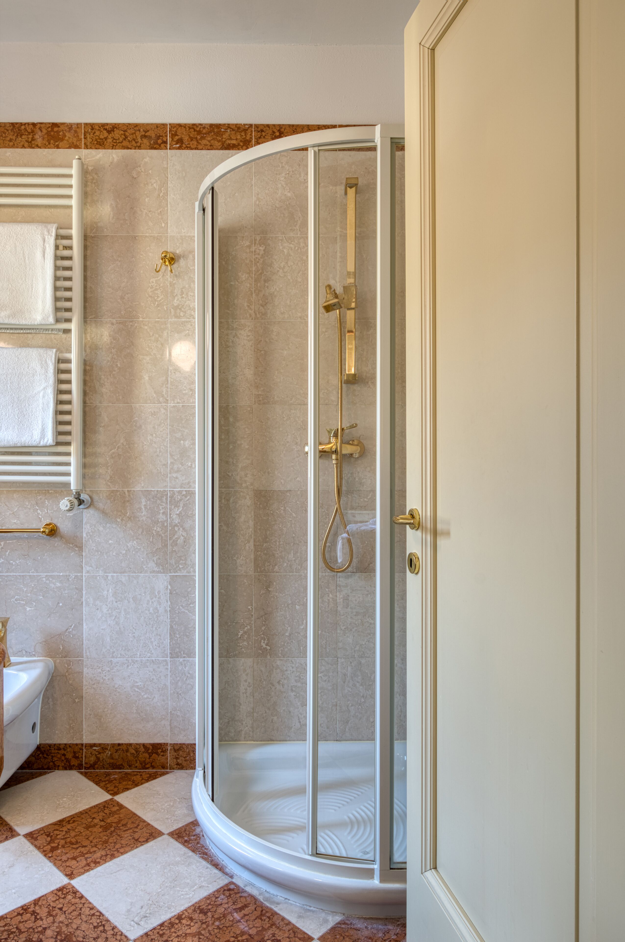 Ein Badezimmer mit einer gläsernen Duschkabine, einer weißen Toilette und einem Handtuchhalter.