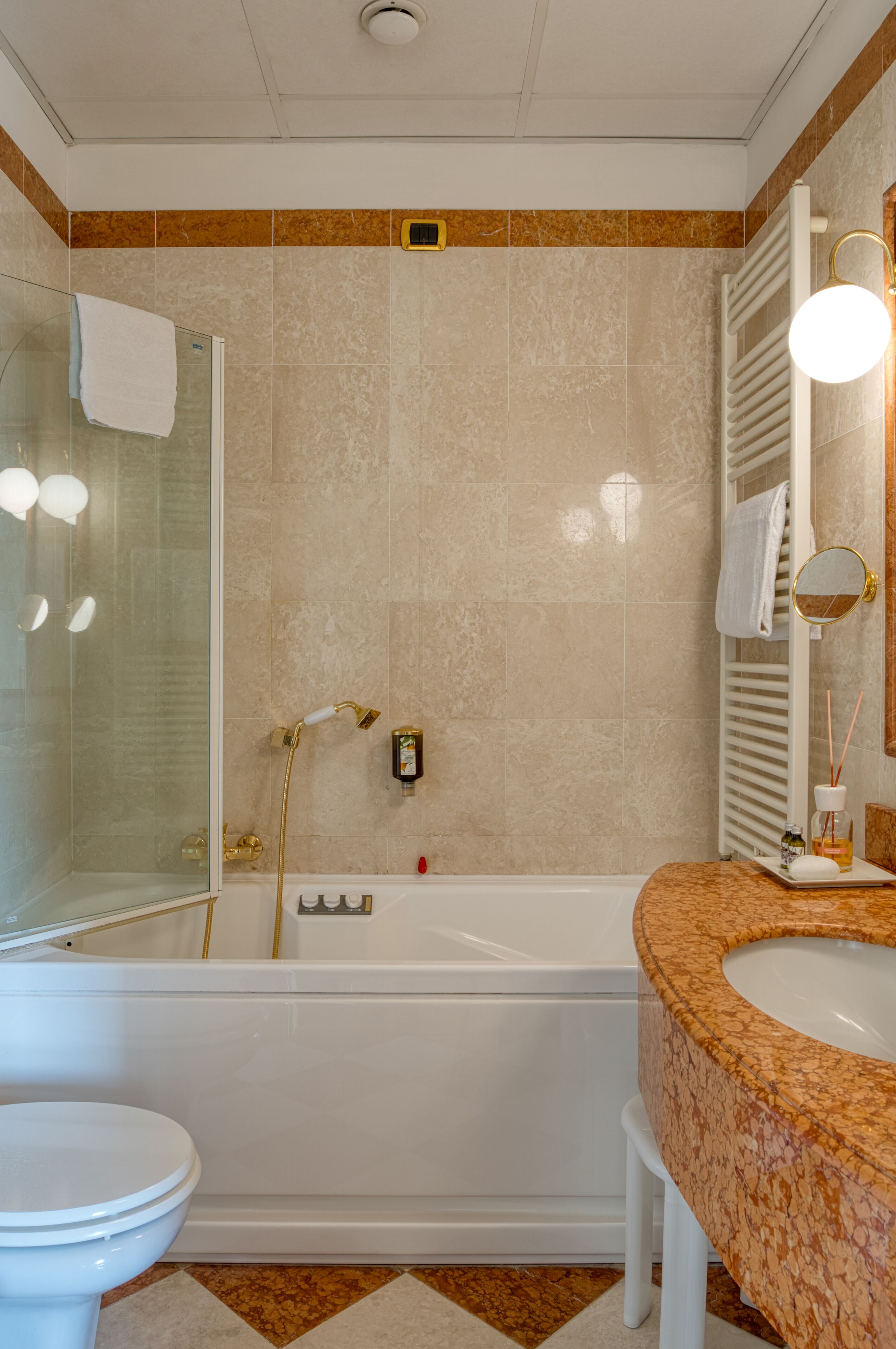 Un baño con cabina de ducha de vidrio, bañera, inodoro y tocador con lavamanos.