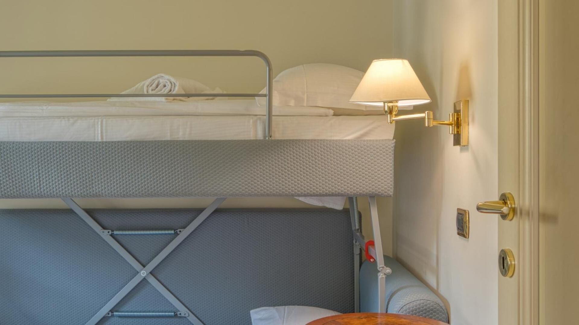 A bunk bed with a foldable desk and a lamp.