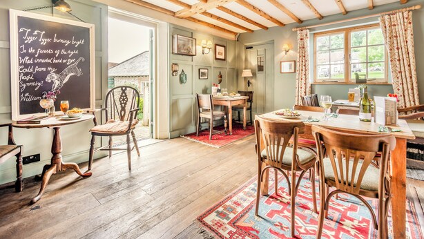 Un coin repas accueillant, avec des meubles en bois, un tableau noir où sont écrites des poésies, et une vue sur l’extérieur.