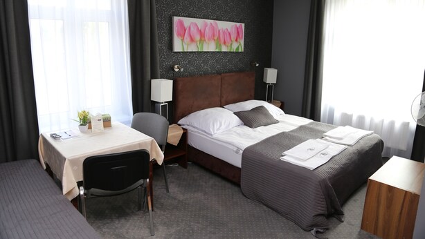 A hotel room with a bed, bedside tables, a desk, and a chair.