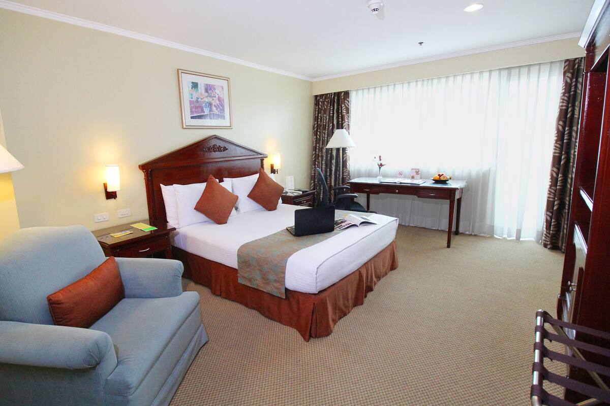 A hotel room with a bed, a desk, a chair, and a couch.
