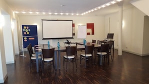 A conference room with a large screen, a whiteboard, and a table with chairs. - Schlafgut Domhof (Guntersblum)