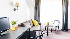 A modern living room with a sofa, two chairs, a small table, a TV, and a lamp. - Schlafgut Domhof (Guntersblum)