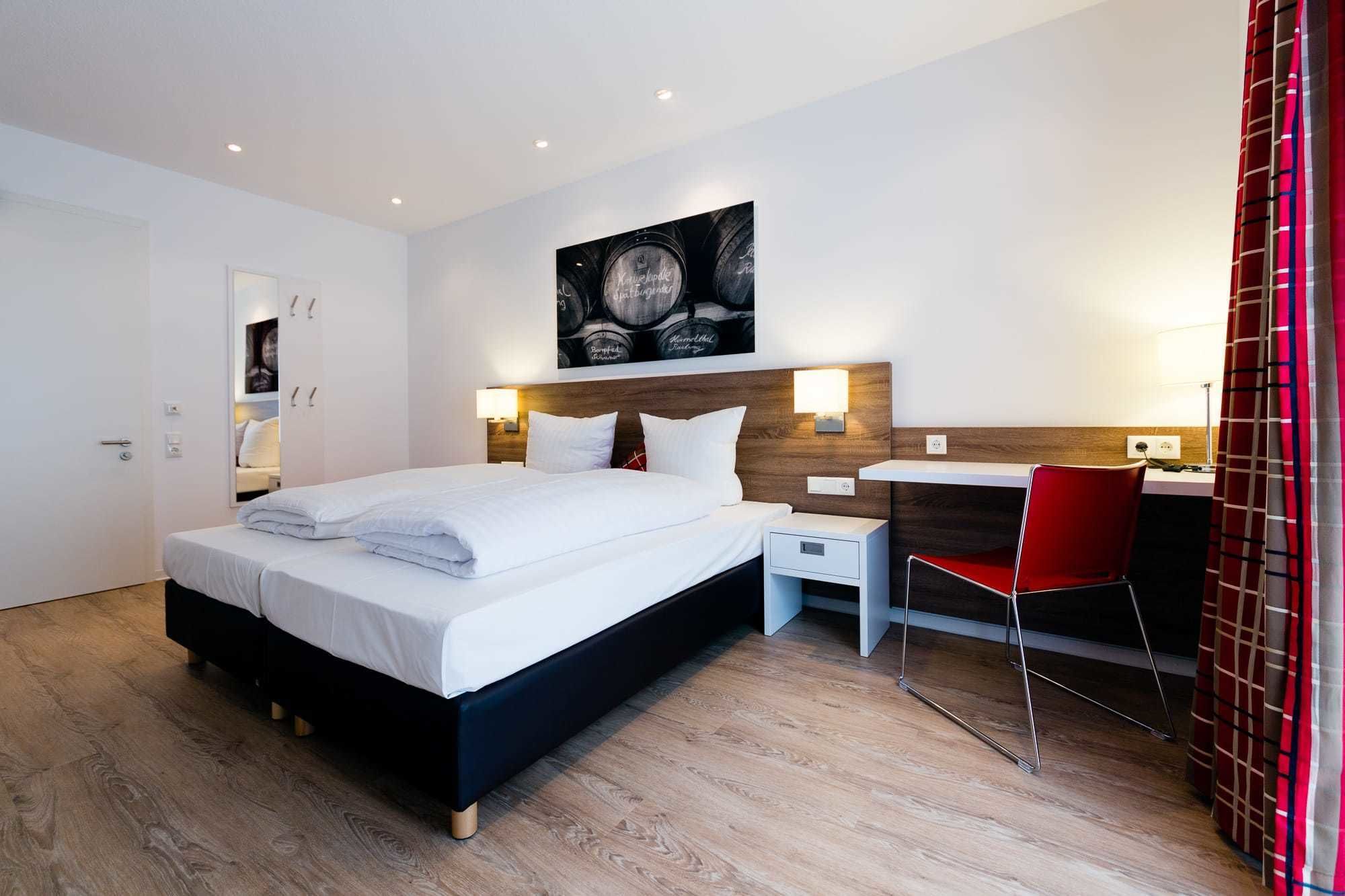 A modern hotel room with a large bed, a desk, and a chair.