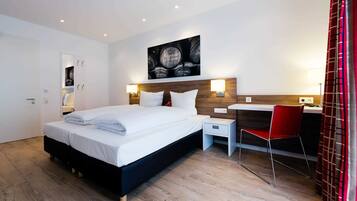 A modern hotel room with a large bed, a desk, and a chair.
