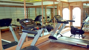 Una palestra con diverse tapis roulant, cyclette e uno specchio a parete.
