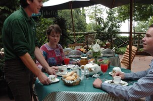 A table set for a meal with various dishes, glasses, and a basket of bread.