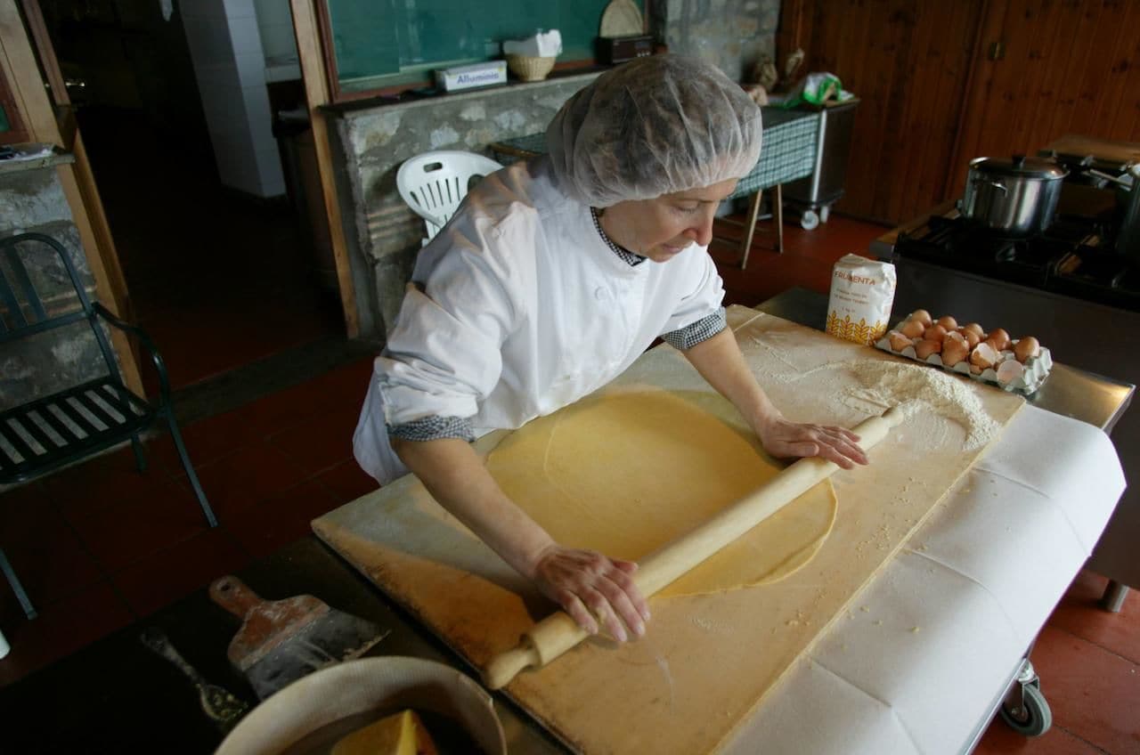 Uma pessoa amassando massa em cima de uma mesa em uma cozinha.