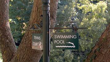 A signpost with two signs: one for a tennis court and another for a swimming pool.
