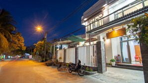 A street view at night with a motorcycle parked in front of a building with a sign that reads "Lounge & Bar". - An Bang Scent Beach Homestay (Da Nang)