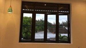 A room with a large window, recessed ceiling lights, and a hanging pendant light. - An Bang Scent Beach Homestay (Da Nang)