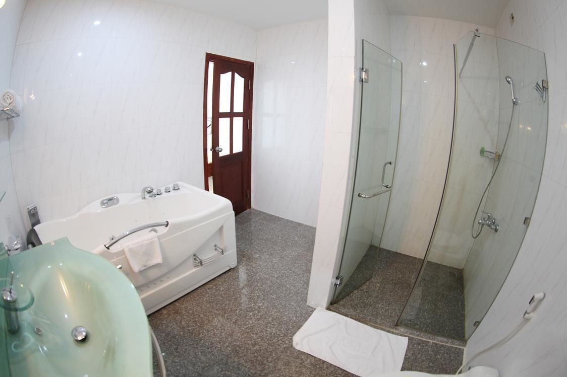 A bathroom with a glass-enclosed shower, a bathtub, and a sink.