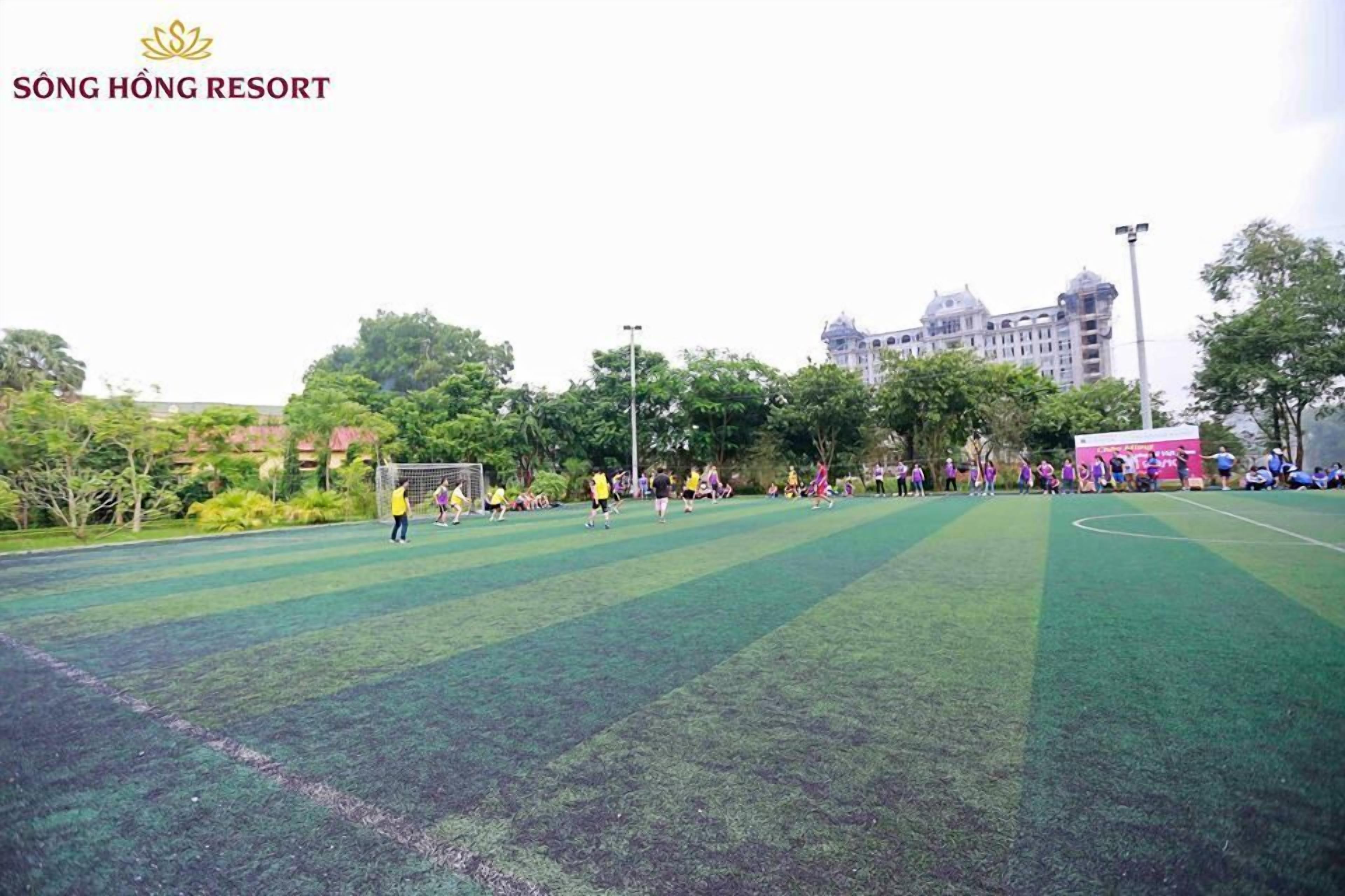 A soccer field at Song Hong Resort with players in yellow and purple jerseys.
