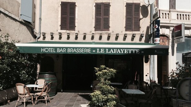 A hotel bar named "Hotel Bar Brasserie Le Laeyette" with outdoor seating and a potted plant in the foreground. - Lafayette (Saint Sever)