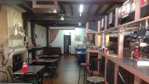 A restaurant with multiple tables and chairs, a bar area with stools, and a fireplace. - Lafayette (Saint Sever)