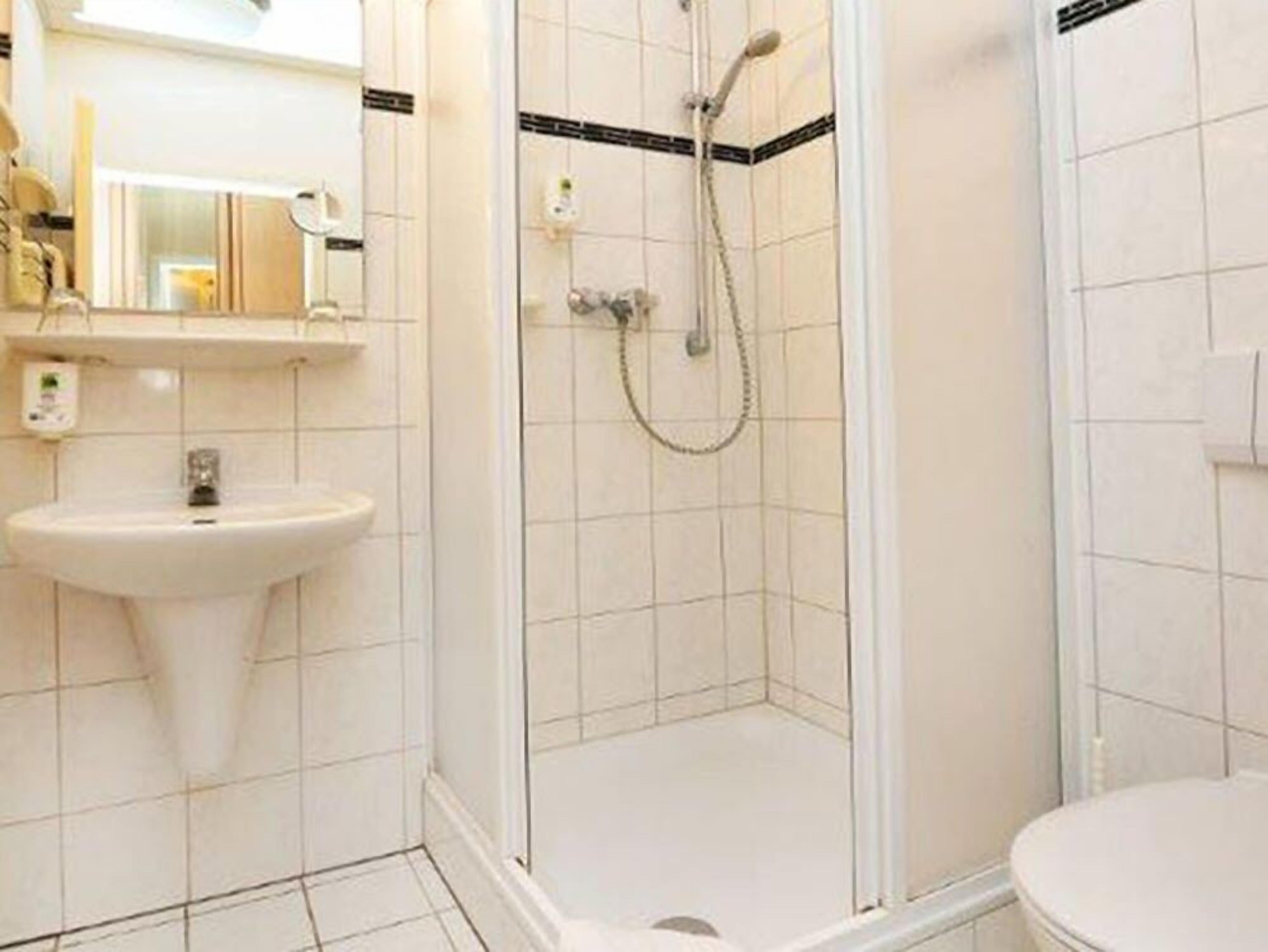 A bathroom with a sink, mirror, shower, and toilet.
