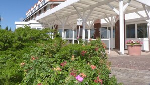 A hotel with a covered outdoor area, a sign indicating it is a hotel, and a brick pathway leading to the entrance. - Hotel Trebeltal (Demmin)